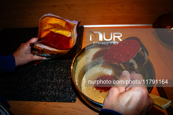 A person adds red pepper flakes to the paste to make fermented South Korean food, Kimchi, on November 10, 2024. 