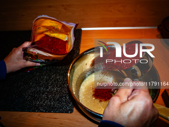 A person adds red pepper flakes to the paste to make fermented South Korean food, Kimchi, on November 10, 2024. (