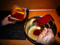 A person adds red pepper flakes to the paste to make fermented South Korean food, Kimchi, on November 10, 2024. (