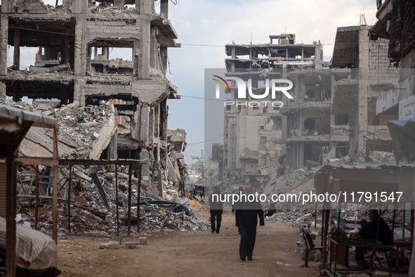 Palestinians walk next to the rubble of a house destroyed in previous airstrikes during the Israeli military offensive, amid the ongoing con...