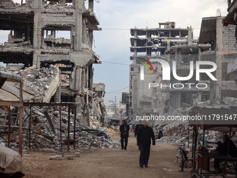 Palestinians walk next to the rubble of a house destroyed in previous airstrikes during the Israeli military offensive, amid the ongoing con...