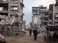 Palestinians walk next to the rubble of a house destroyed in previous airstrikes during the Israeli military offensive, amid the ongoing con...