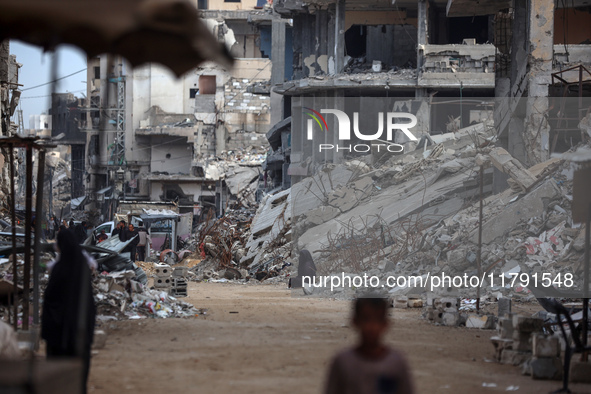 Palestinians walk next to the rubble of a house destroyed in previous airstrikes during the Israeli military offensive, amid the ongoing con...