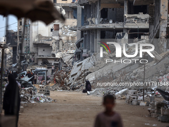 Palestinians walk next to the rubble of a house destroyed in previous airstrikes during the Israeli military offensive, amid the ongoing con...