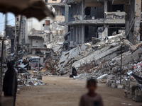 Palestinians walk next to the rubble of a house destroyed in previous airstrikes during the Israeli military offensive, amid the ongoing con...