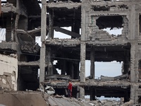 A Palestinian boy walks next to the rubble of a house destroyed in previous airstrikes during the Israeli military offensive, amid the ongoi...