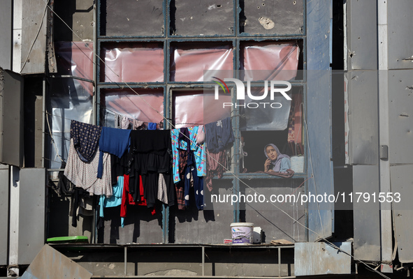 A Palestinian woman looks out from a building destroyed in previous airstrikes during the Israeli military offensive, amid the ongoing confl...