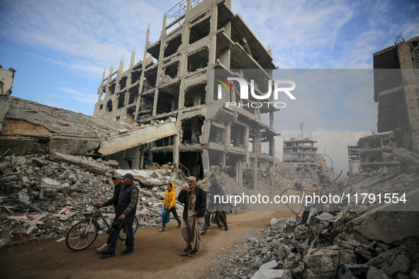 Palestinians walk next to the rubble of a house destroyed in previous airstrikes during the Israeli military offensive, amid the ongoing con...