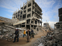 Palestinians walk next to the rubble of a house destroyed in previous airstrikes during the Israeli military offensive, amid the ongoing con...