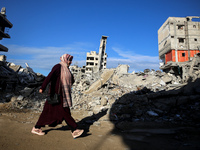 A Palestinian woman walks next to the rubble of a house destroyed in previous airstrikes during the Israeli military offensive, amid the ong...