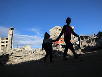 Palestinian children walk next to the rubble of a house destroyed in previous airstrikes during the Israeli military offensive, amid the ong...