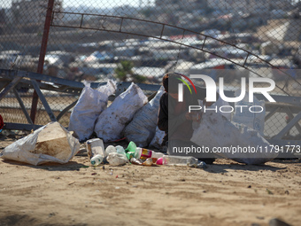 A displaced Palestinian boy searches through a pile of garbage in Khan Yunis, Gaza Strip, on November 19, 2024, amid the ongoing war between...