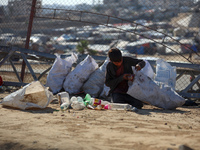 A displaced Palestinian boy searches through a pile of garbage in Khan Yunis, Gaza Strip, on November 19, 2024, amid the ongoing war between...