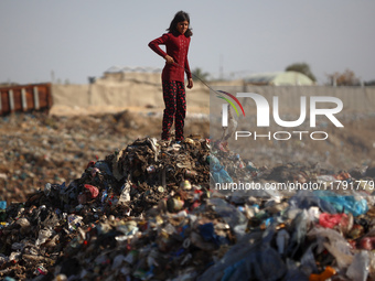 A displaced Palestinian girl searches through a pile of garbage in Khan Yunis, Gaza Strip, on November 19, 2024, amid the ongoing war betwee...