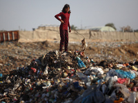 A displaced Palestinian girl searches through a pile of garbage in Khan Yunis, Gaza Strip, on November 19, 2024, amid the ongoing war betwee...