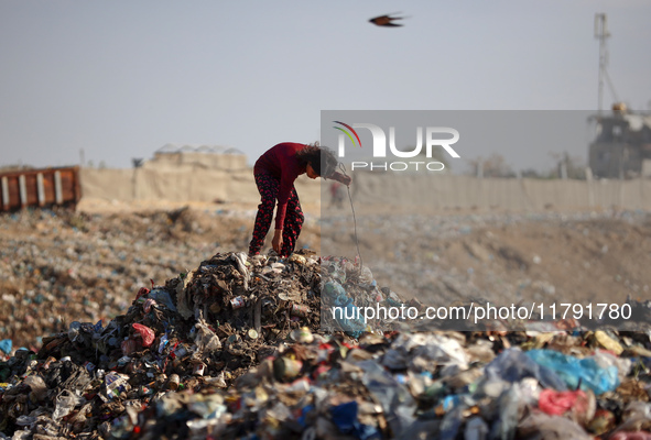 A displaced Palestinian girl searches through a pile of garbage in Khan Yunis, Gaza Strip, on November 19, 2024, amid the ongoing war betwee...