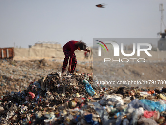 A displaced Palestinian girl searches through a pile of garbage in Khan Yunis, Gaza Strip, on November 19, 2024, amid the ongoing war betwee...