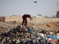 A displaced Palestinian girl searches through a pile of garbage in Khan Yunis, Gaza Strip, on November 19, 2024, amid the ongoing war betwee...