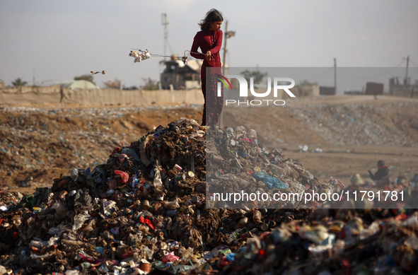 A displaced Palestinian girl searches through a pile of garbage in Khan Yunis, Gaza Strip, on November 19, 2024, amid the ongoing war betwee...