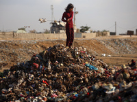 A displaced Palestinian girl searches through a pile of garbage in Khan Yunis, Gaza Strip, on November 19, 2024, amid the ongoing war betwee...