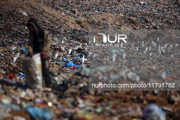 A displaced Palestinian boy searches through a pile of garbage in Khan Yunis, Gaza Strip, on November 19, 2024, amid the ongoing war between...