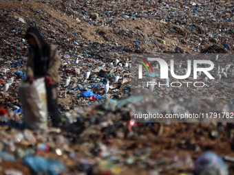 A displaced Palestinian boy searches through a pile of garbage in Khan Yunis, Gaza Strip, on November 19, 2024, amid the ongoing war between...