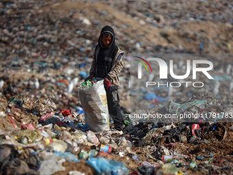 A displaced Palestinian boy searches through a pile of garbage in Khan Yunis, Gaza Strip, on November 19, 2024, amid the ongoing war between...