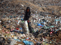 A displaced Palestinian boy searches through a pile of garbage in Khan Yunis, Gaza Strip, on November 19, 2024, amid the ongoing war between...