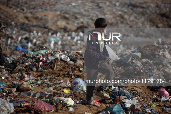 A displaced Palestinian boy searches through a pile of garbage in Khan Yunis, Gaza Strip, on November 19, 2024, amid the ongoing war between...