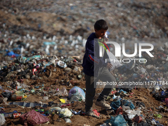 A displaced Palestinian boy searches through a pile of garbage in Khan Yunis, Gaza Strip, on November 19, 2024, amid the ongoing war between...