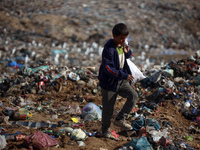 A displaced Palestinian boy searches through a pile of garbage in Khan Yunis, Gaza Strip, on November 19, 2024, amid the ongoing war between...