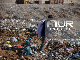 A displaced Palestinian boy searches through a pile of garbage in Khan Yunis, Gaza Strip, on November 19, 2024, amid the ongoing war between...