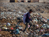 A displaced Palestinian boy searches through a pile of garbage in Khan Yunis, Gaza Strip, on November 19, 2024, amid the ongoing war between...