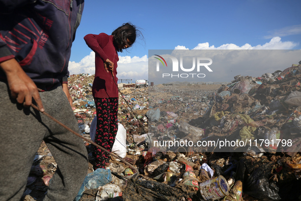 A displaced Palestinian girl searches through a pile of garbage in Khan Yunis, Gaza Strip, on November 19, 2024, amid the ongoing war betwee...