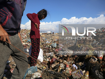 A displaced Palestinian girl searches through a pile of garbage in Khan Yunis, Gaza Strip, on November 19, 2024, amid the ongoing war betwee...