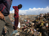 A displaced Palestinian girl searches through a pile of garbage in Khan Yunis, Gaza Strip, on November 19, 2024, amid the ongoing war betwee...