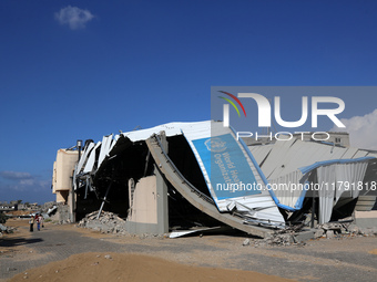 A displaced Palestinian girl walks past a damaged World Health Organisation storage center hit in recent Israeli bombardment in Khan Yunis,...