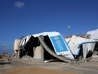 A displaced Palestinian girl walks past a damaged World Health Organisation storage center hit in recent Israeli bombardment in Khan Yunis,...