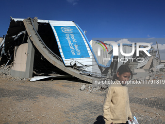 A displaced Palestinian girl walks past a damaged World Health Organisation storage center hit in recent Israeli bombardment in Khan Yunis,...