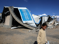 A displaced Palestinian girl walks past a damaged World Health Organisation storage center hit in recent Israeli bombardment in Khan Yunis,...