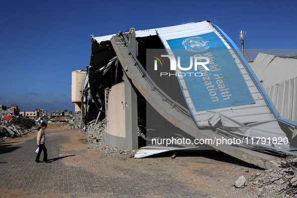 A displaced Palestinian girl walks past a damaged World Health Organisation storage center hit in recent Israeli bombardment in Khan Yunis,...