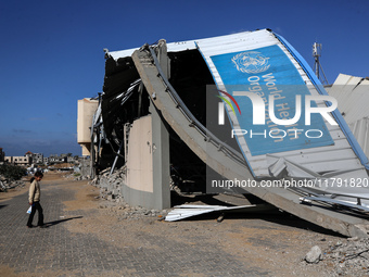 A displaced Palestinian girl walks past a damaged World Health Organisation storage center hit in recent Israeli bombardment in Khan Yunis,...