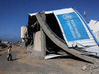 A displaced Palestinian girl walks past a damaged World Health Organisation storage center hit in recent Israeli bombardment in Khan Yunis,...