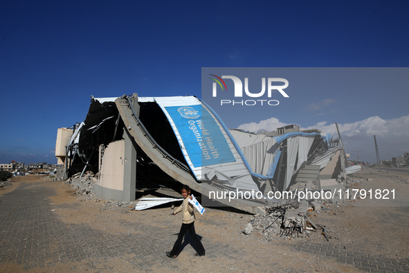 A displaced Palestinian girl walks past a damaged World Health Organisation storage center hit in recent Israeli bombardment in Khan Yunis,...