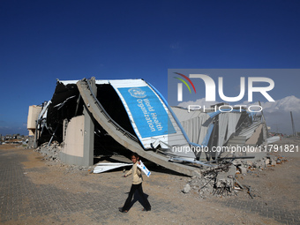 A displaced Palestinian girl walks past a damaged World Health Organisation storage center hit in recent Israeli bombardment in Khan Yunis,...