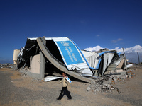 A displaced Palestinian girl walks past a damaged World Health Organisation storage center hit in recent Israeli bombardment in Khan Yunis,...