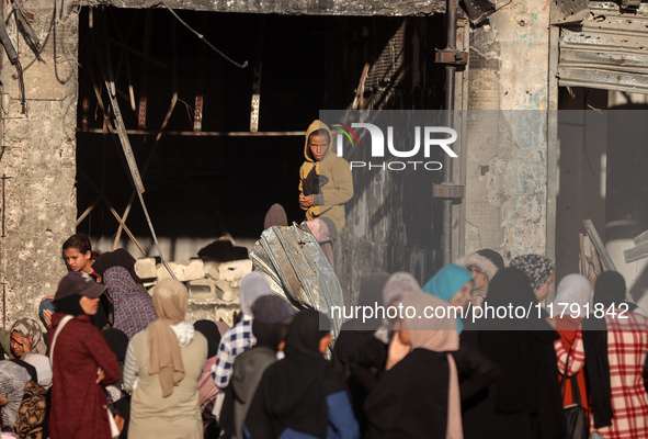 Displaced and local Palestinian residents of Khan Yunis wait outside a bakery for fresh bread in the southern Gaza Strip city on November 19...