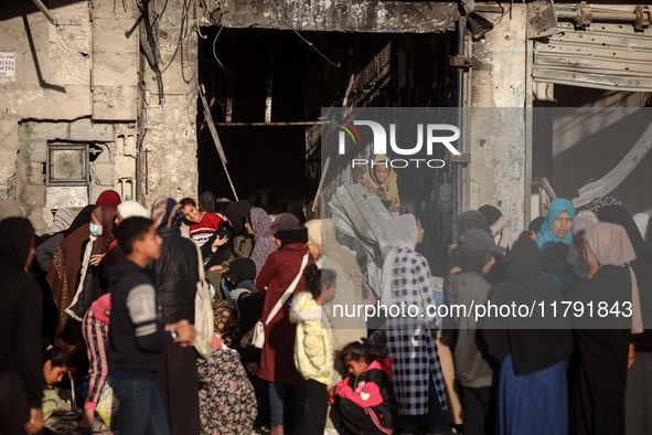 Displaced and local Palestinian residents of Khan Yunis wait outside a bakery for fresh bread in the southern Gaza Strip city on November 19...