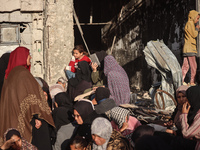 Displaced and local Palestinian residents of Khan Yunis wait outside a bakery for fresh bread in the southern Gaza Strip city on November 19...