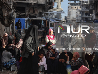 Displaced and local Palestinian residents of Khan Yunis wait outside a bakery for fresh bread in the southern Gaza Strip city on November 19...